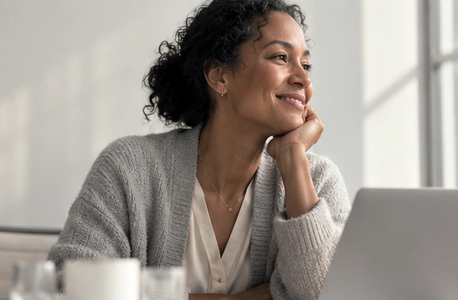 Mara Okafor, a controller, smiling at her desk beside a laptop